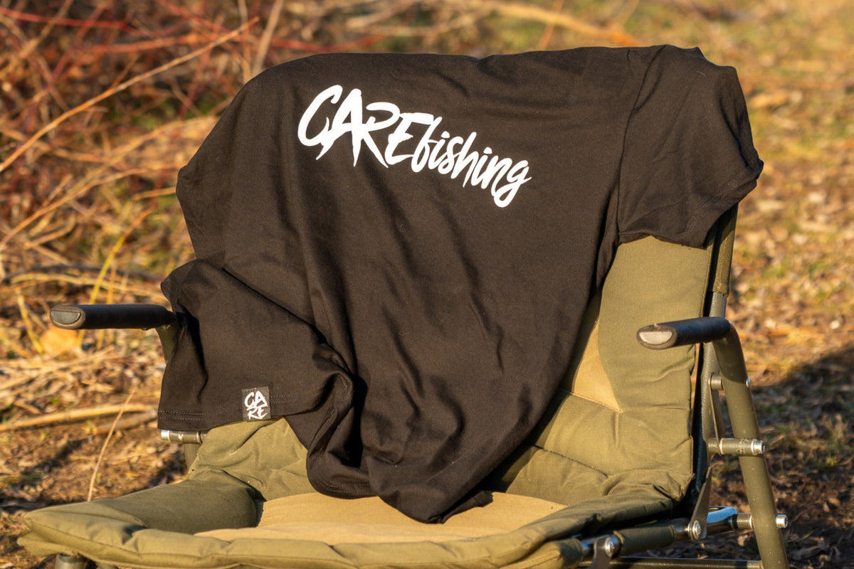 Schwarzes CARE Fishing Shirt auf einem Angelstuhl